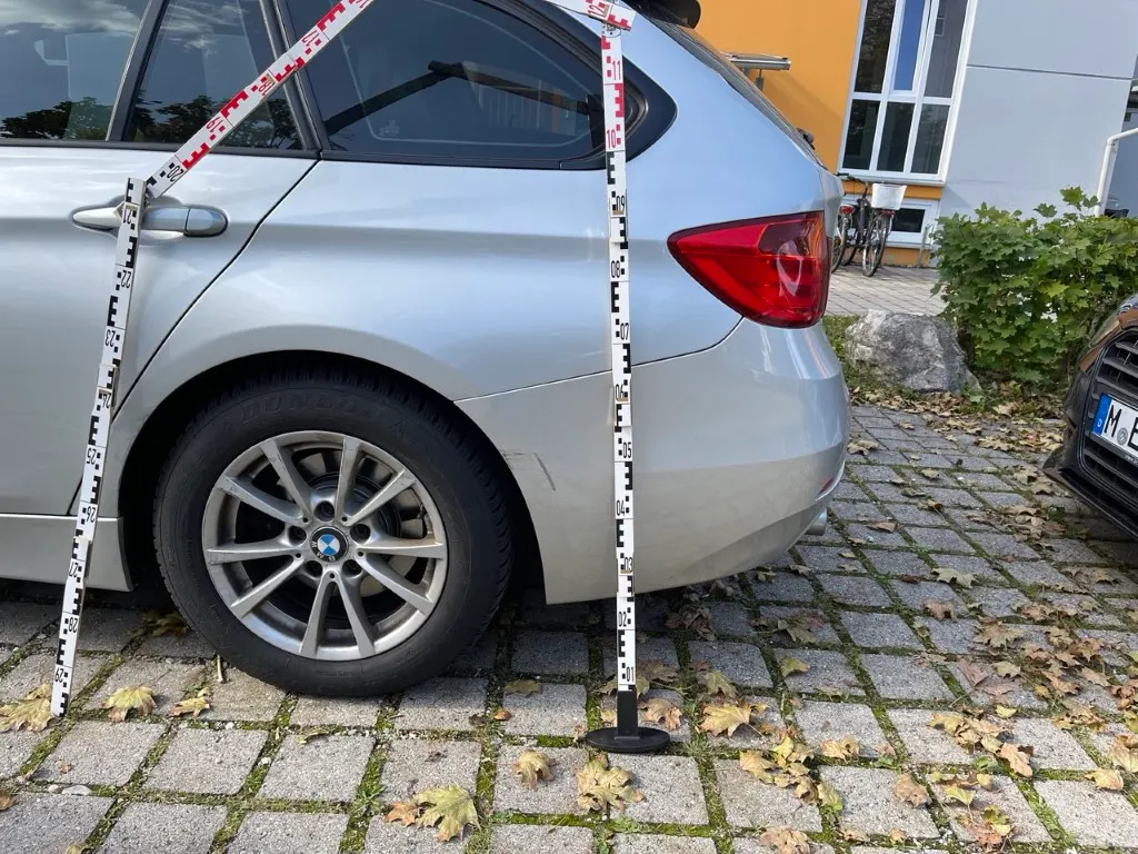 Sachverständiger vermisst einen beschädigten BMW mit Messlatten vor Ort
